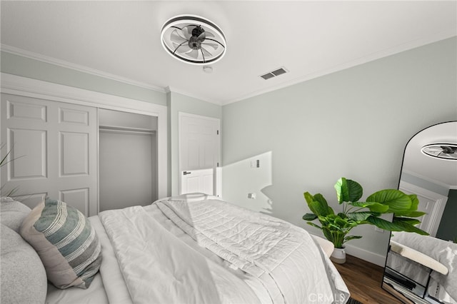 bedroom with baseboards, wood finished floors, visible vents, ornamental molding, and a closet