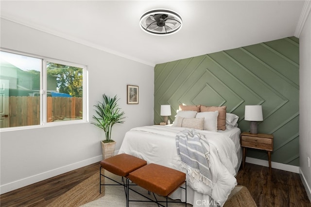 bedroom with an accent wall, baseboards, dark wood finished floors, and ornamental molding