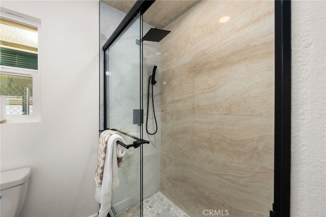 bathroom featuring toilet and a shower stall