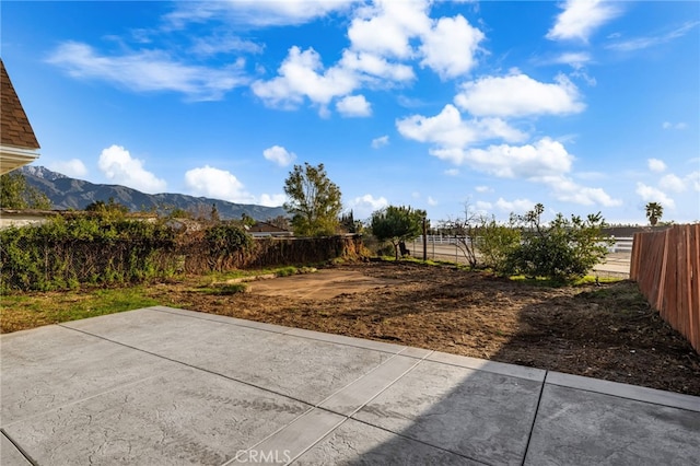 view of yard featuring a patio, a fenced backyard, and a mountain view