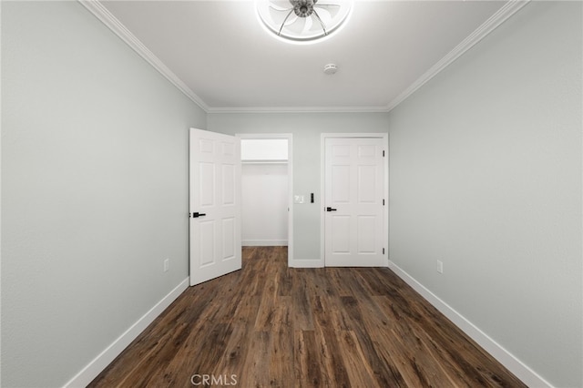unfurnished bedroom featuring a walk in closet, ornamental molding, baseboards, dark wood-style floors, and a closet