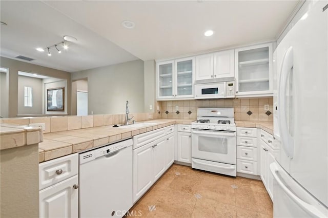 33 Perennial, Irvine, CA 92603 - kitchen featuring white appliances, a peninsula, decorative backsplash, a sink, and white cabinetry