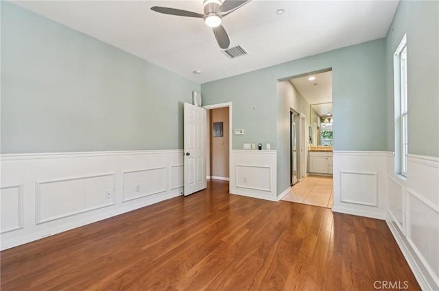 33 Perennial, Irvine, CA 92603 - unfurnished bedroom with wood finished floors, a wainscoted wall, connected bathroom, ceiling fan, and a decorative wall
