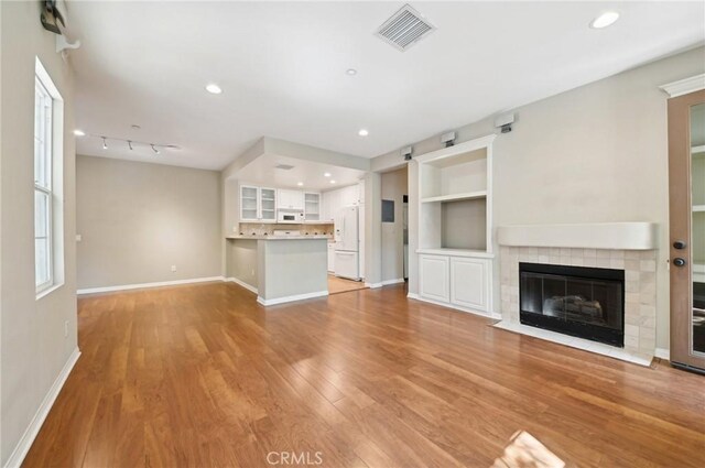 33 Perennial, Irvine, CA 92603 - unfurnished living room with light wood finished floors, baseboards, a tile fireplace, built in shelves, and recessed lighting
