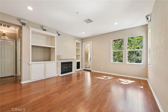 33 Perennial, Irvine, CA 92603 - unfurnished living room with baseboards, a tiled fireplace, wood finished floors, built in shelves, and recessed lighting
