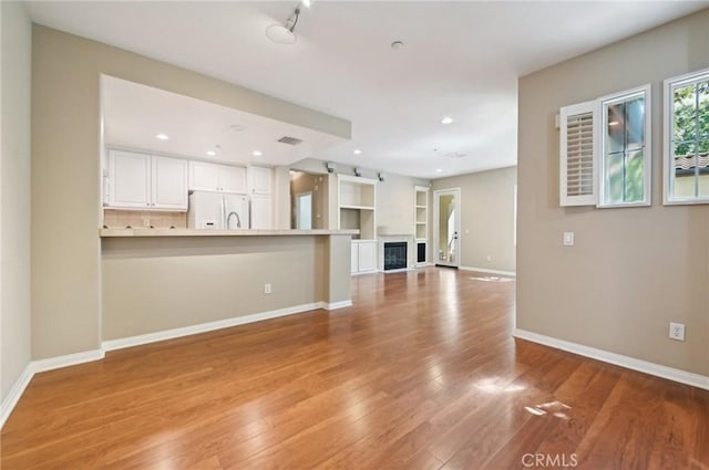 33 Perennial, Irvine, CA 92603 - unfurnished living room featuring light wood-style flooring, baseboards, recessed lighting, and a glass covered fireplace