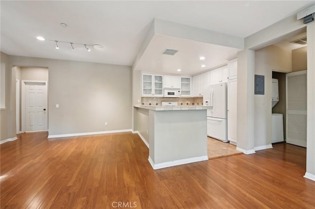 33 Perennial, Irvine, CA 92603 - kitchen with white appliances, stacked washer / drying machine, a peninsula, glass insert cabinets, and light wood-style flooring