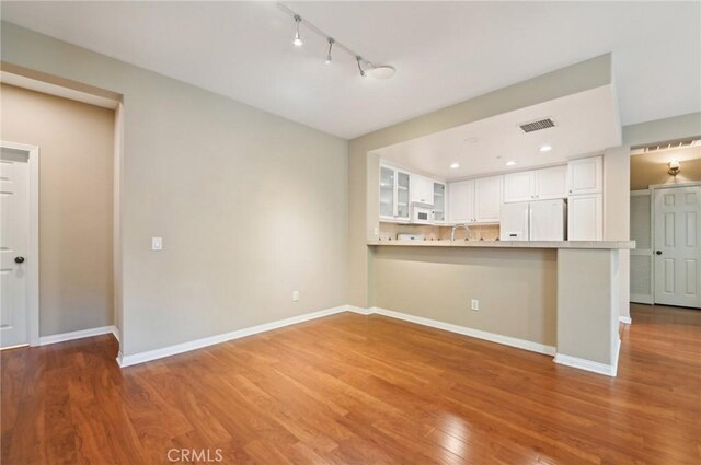 33 Perennial, Irvine, CA 92603 - kitchen featuring white appliances, glass insert cabinets, white cabinets, light wood-type flooring, and rail lighting