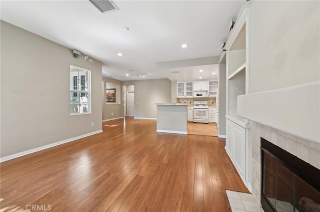 33 Perennial, Irvine, CA 92603 - unfurnished living room featuring track lighting, light wood-type flooring, a tile fireplace, and baseboards
