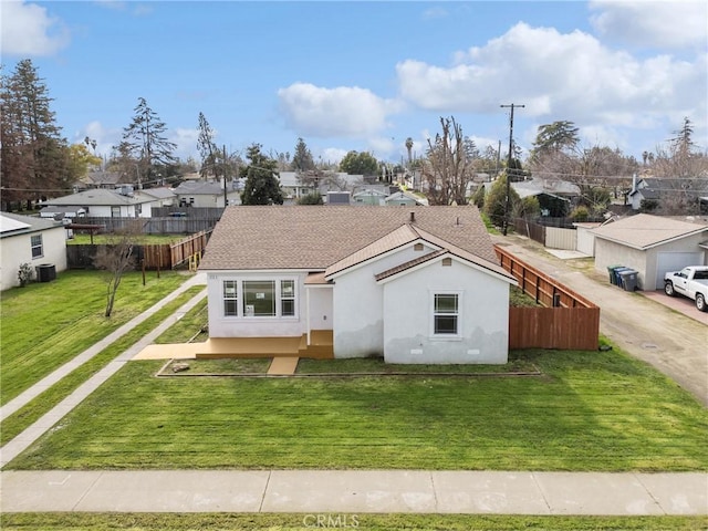 view of front of property featuring fence, a residential view, a front yard, stucco siding, and central AC unit