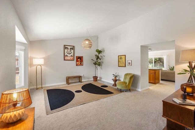 carpeted living area featuring vaulted ceiling and baseboards