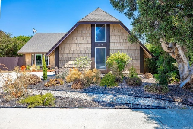 a-frame home featuring roof with shingles and fence