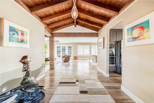 corridor with vaulted ceiling with beams, light wood-type flooring, wooden ceiling, and baseboards