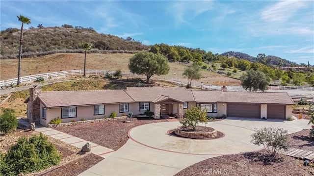 ranch-style home with concrete driveway, fence, a tiled roof, and stucco siding