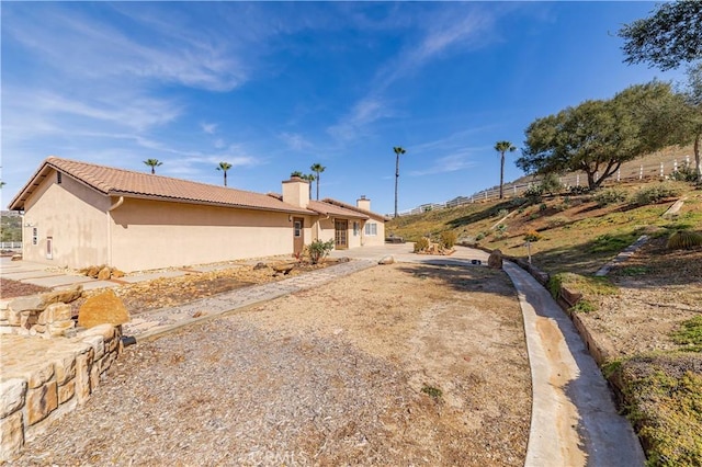 exterior space featuring a chimney, fence, and stucco siding