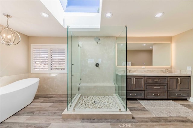 bathroom with double vanity, a soaking tub, wood finished floors, and a shower stall