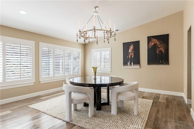 dining space with baseboards, a chandelier, and wood finished floors