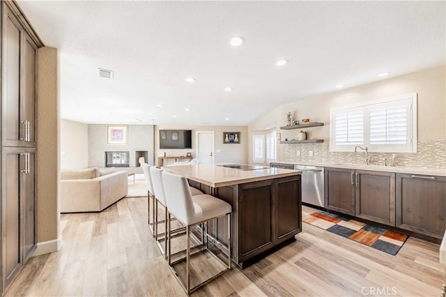 kitchen featuring a kitchen island, open floor plan, light countertops, a kitchen bar, and stainless steel dishwasher