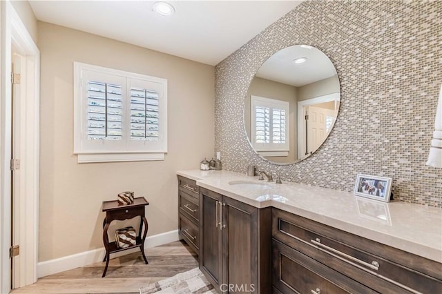 bathroom featuring recessed lighting, wood finished floors, vanity, baseboards, and tasteful backsplash