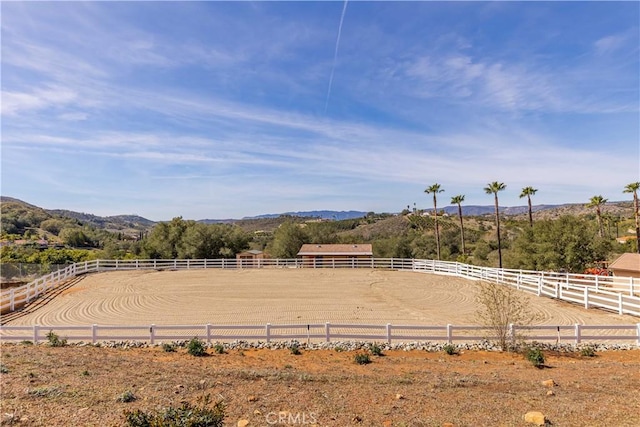 view of yard with an enclosed area, a mountain view, and a rural view