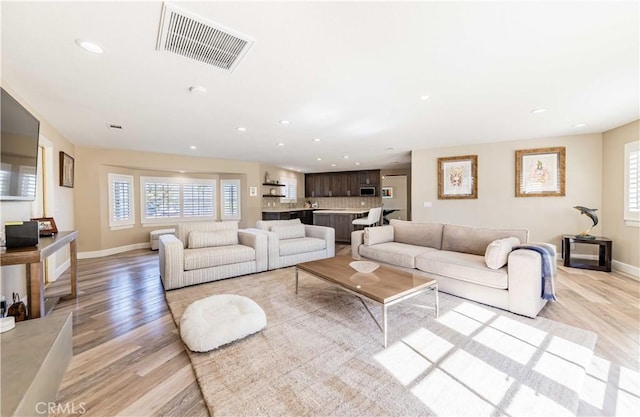 living area with light wood-style floors, a wealth of natural light, visible vents, and recessed lighting