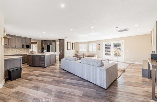 living room with recessed lighting, visible vents, and light wood finished floors