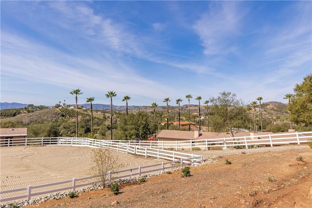 view of yard featuring an enclosed area, a rural view, fence, and a mountain view