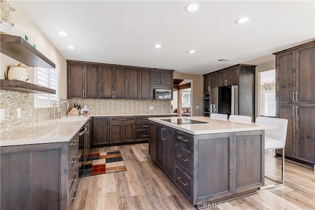 kitchen with light wood-type flooring, stainless steel appliances, light countertops, and a center island