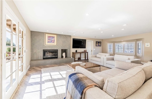 living area featuring a glass covered fireplace, light wood-style flooring, and recessed lighting