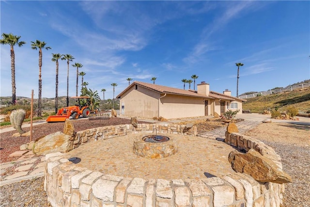 exterior space with an outdoor fire pit, a chimney, and stucco siding