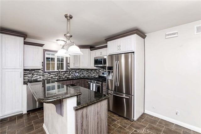 kitchen with stainless steel appliances, white cabinets, decorative backsplash, pendant lighting, and a kitchen island