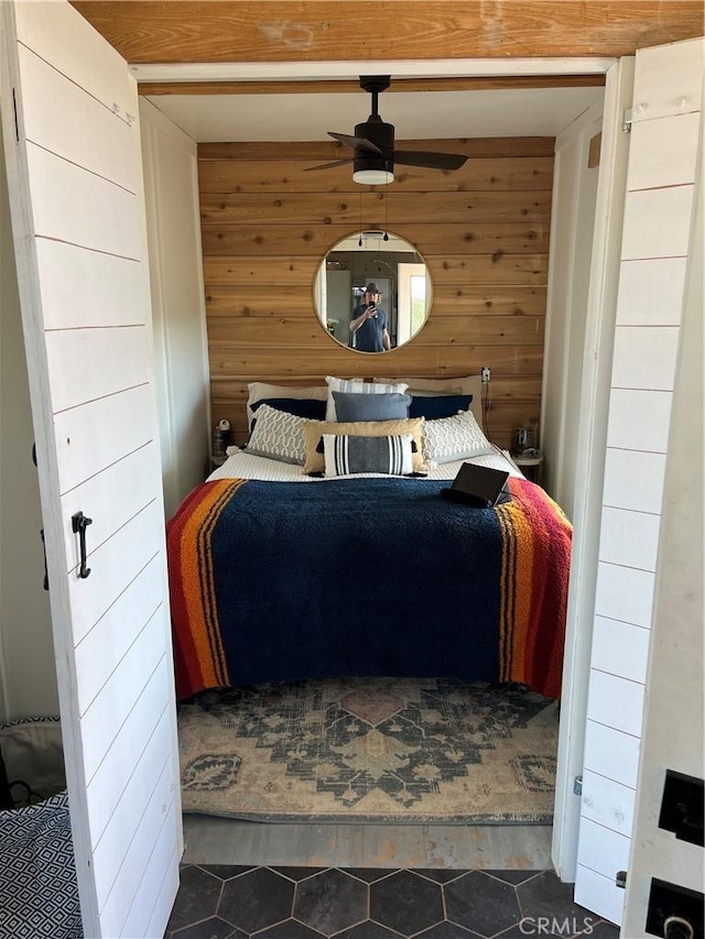 bedroom with dark tile patterned floors and wooden walls