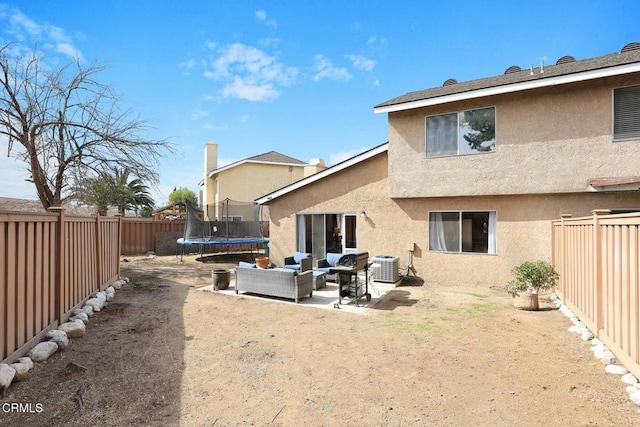 back of house with cooling unit, an outdoor living space, a patio, and a trampoline