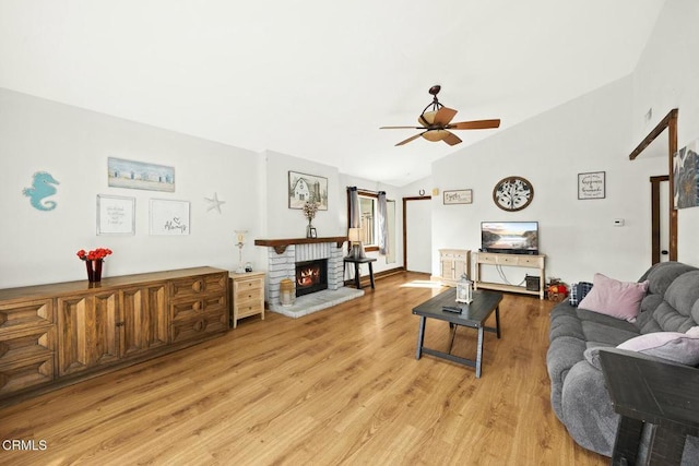 living room with a brick fireplace, lofted ceiling, ceiling fan, and light hardwood / wood-style flooring