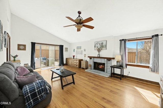 living room featuring light wood-type flooring, high vaulted ceiling, ceiling fan, and a fireplace