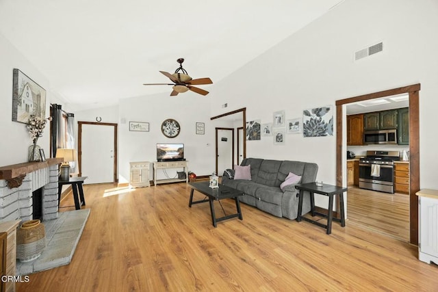 living room with a fireplace, light hardwood / wood-style flooring, high vaulted ceiling, and ceiling fan