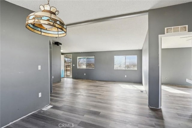 interior space with a textured ceiling, lofted ceiling with beams, and dark hardwood / wood-style floors