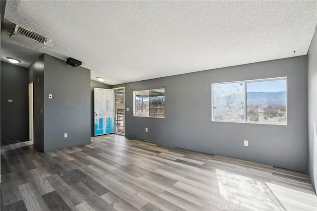 unfurnished room with wood-type flooring and a textured ceiling