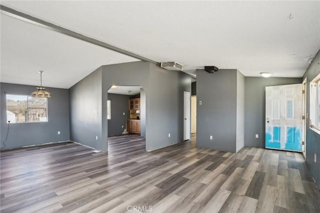 unfurnished living room featuring dark wood-type flooring and vaulted ceiling with beams