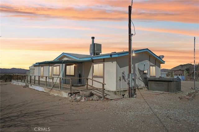 back house at dusk featuring a hot tub, central air condition unit, and a mountain view