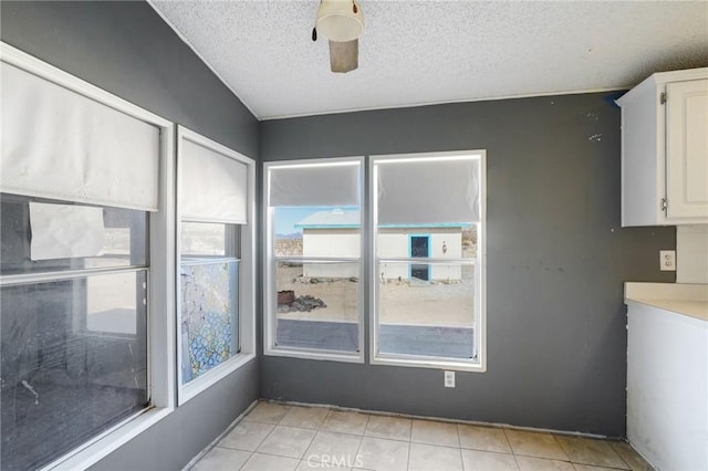 interior space featuring light tile patterned flooring, ceiling fan, and a textured ceiling