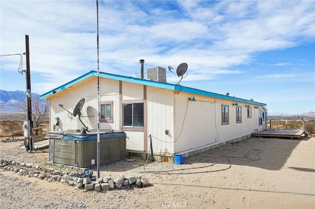 view of side of home with cooling unit, a mountain view, and a hot tub