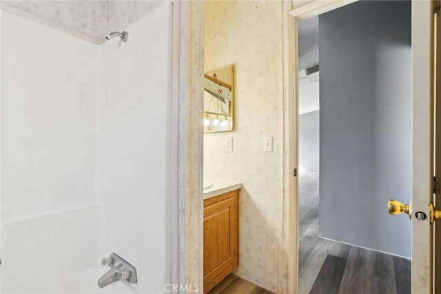 bathroom with hardwood / wood-style floors, bathing tub / shower combination, and vanity