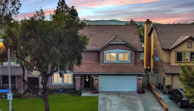 view of front facade with a chimney, a tiled roof, a front yard, stucco siding, and driveway