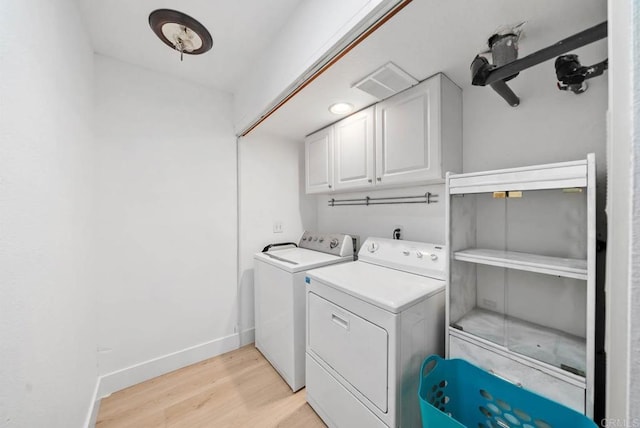 washroom with light hardwood / wood-style floors, cabinets, and separate washer and dryer