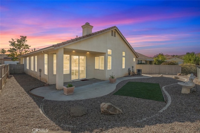 back house at dusk featuring central AC and a patio area