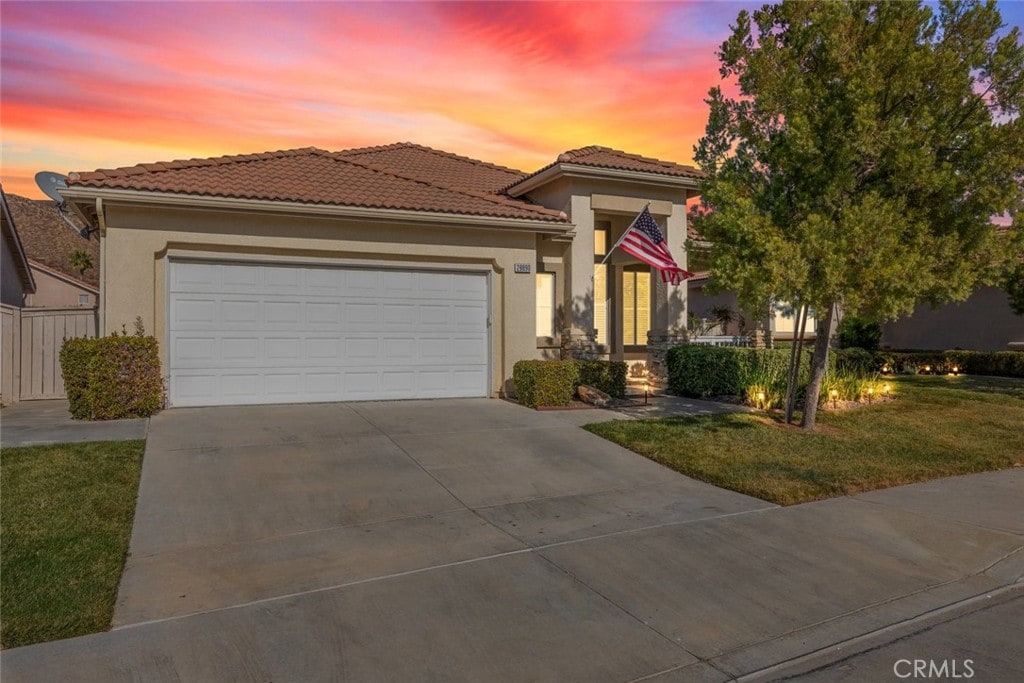 mediterranean / spanish house with a garage and a lawn