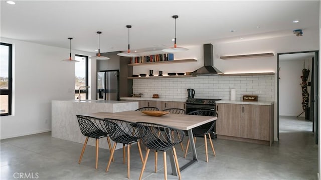 8750 Desert Shadows, Joshua Tree, CA 92252 - kitchen featuring wall chimney range hood, stainless steel refrigerator with ice dispenser, finished concrete floors, open shelves, and recessed lighting