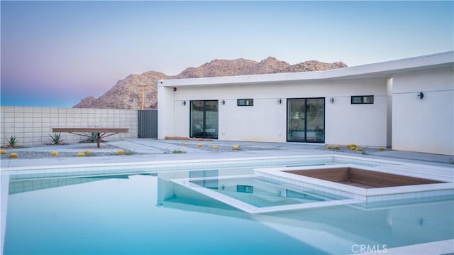 8750 Desert Shadows, Joshua Tree, CA 92252 - view of swimming pool featuring a pool with connected hot tub, a mountain view, and a fenced backyard