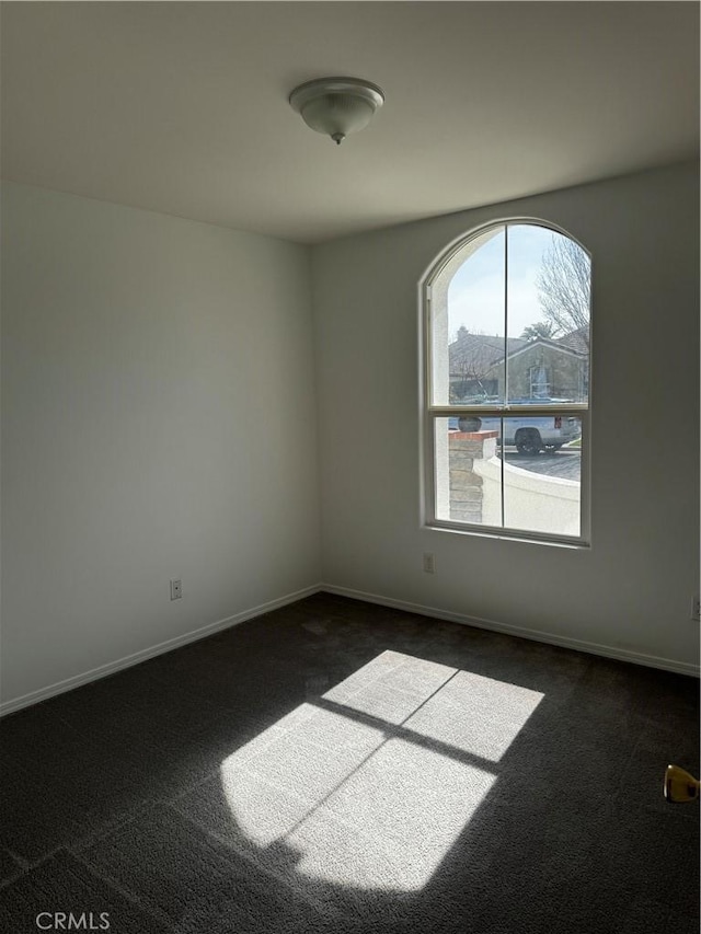 spare room with dark colored carpet